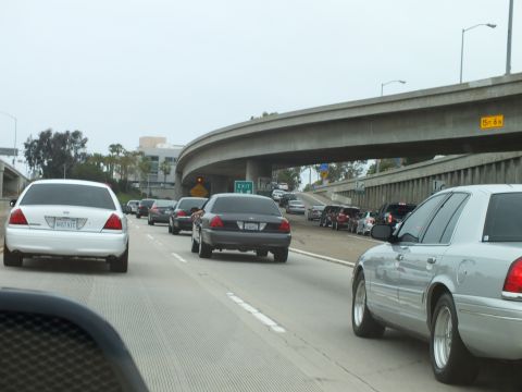 2003 Ford Crown Victoria - Photo of Crown Victorias in freeway traffic approaching a concrete overpass interchange.