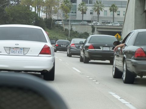 2003 Ford Crown Victoria - Photo of white and black Crown Victorias in freeway traffic with a driver reaching out the window.