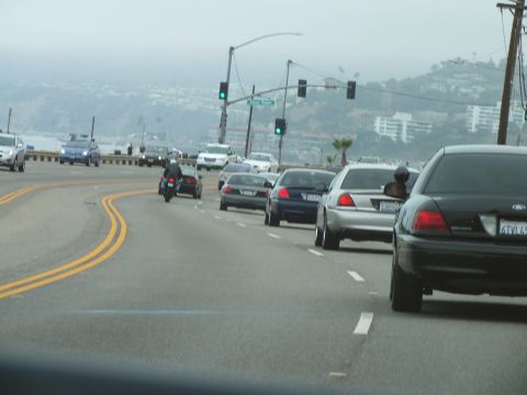 2003 Ford Crown Victoria - Photo of sedans and a motorcycle in coastal-highway traffic at a signal under foggy skies.