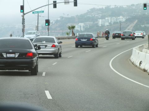 2003 Ford Crown Victoria - Photo of Crown Victorias and other cars on a foggy coastal highway near a Haut Road signal.