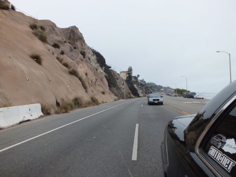 2003 Ford Crown Victoria - Photo of a black Crown Victoria driving along a coastal highway beside an eroded sandy hillside.