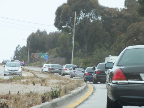 2003 Ford Crown Victoria - Driving photo of cars lined up along a roadside near directional highway signs, not a technical document.