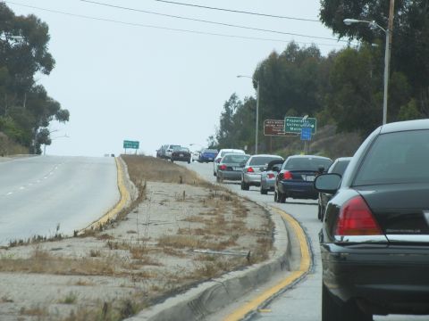 2003 Ford Crown Victoria - Road photo of vehicles along a curving highway shoulder near green freeway signs, not a technical document.