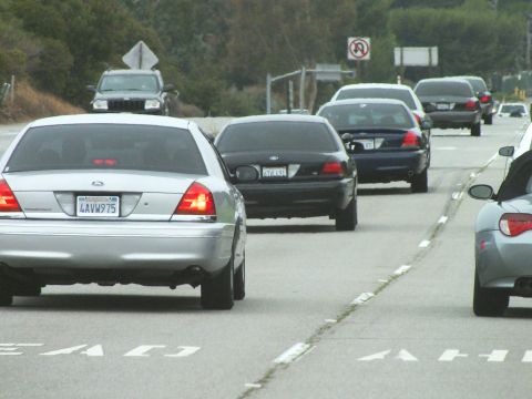 2003 Ford Crown Victoria - Road photo of cars on a multi-lane road with painted arrows and a no-U-turn sign, not a technical document.