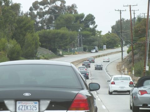 2003 Ford Crown Victoria - Driving photo of a black Ford leading traffic on a curving road near power lines, not a technical document.