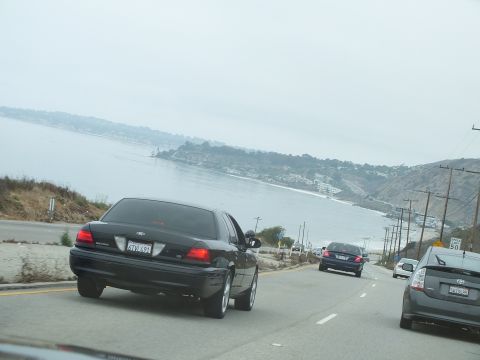 2003 Ford Crown Victoria - Driving photo of cars on a coastal highway overlooking a bay, not a technical document.
