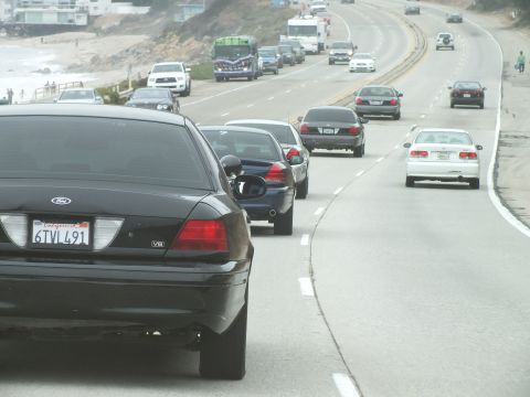 2003 Ford Crown Victoria - Driving photo of a black Ford leading traffic on a curving coastal highway, not a technical document.