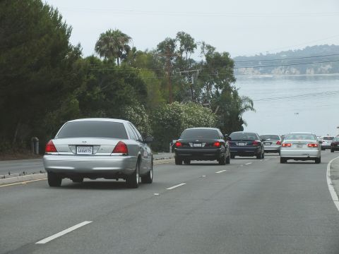 2003 Ford Crown Victoria - Photograph of a silver Crown Victoria driving on a coastal highway above the ocean, not a technical document.