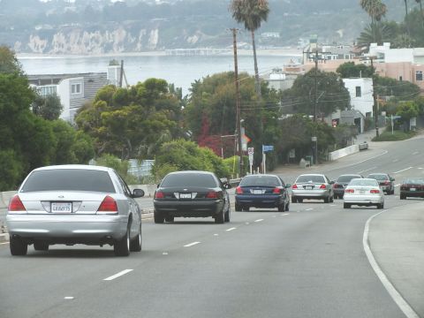 2003 Ford Crown Victoria - Photograph of a silver Crown Victoria and other cars on a coastal highway near the shore, not a technical document.