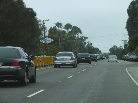 2003 Ford Crown Victoria - Photograph of a black Crown Victoria and silver sedan driving on a coastal highway, not a technical document.