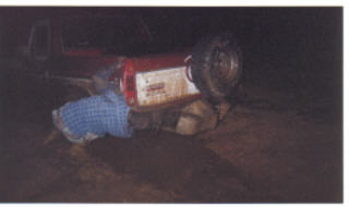 1978 Ford Bronco - A person is attempting to work on a vehicle that has overturned in a muddy area.