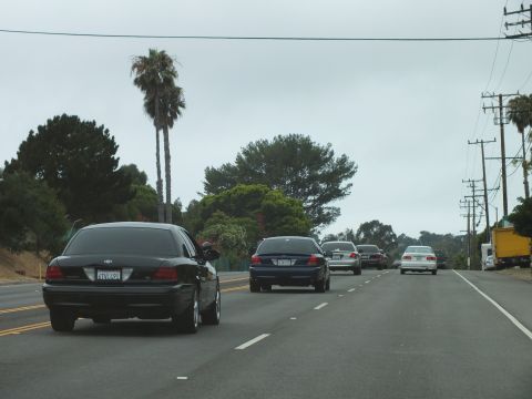 2003 Ford Crown Victoria - Photograph of a black Ford Crown Victoria leading sedans on a divided highway, not a technical document.