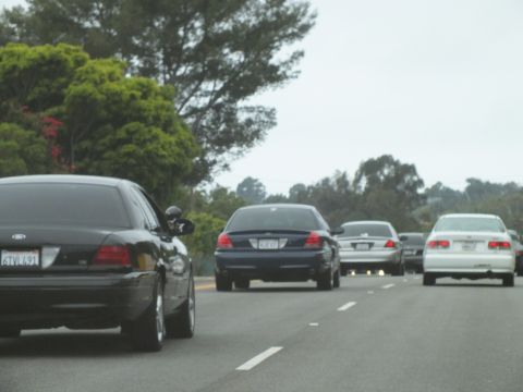 2003 Ford Crown Victoria - Photograph of cars including a black Crown Victoria driving on a highway, not a technical document.