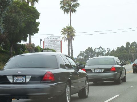 2003 Ford Crown Victoria - Photograph of Crown Victoria sedans passing a Point Dume sign, not a technical document.