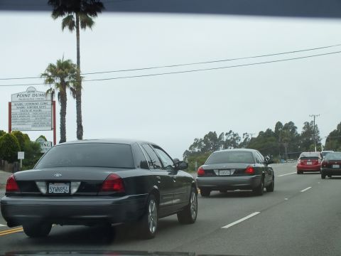 2003 Ford Crown Victoria - Photograph of sedans driving on a coastal highway by a Point Dume sign, not a technical document.