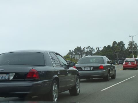 2003 Ford Crown Victoria - Photograph of sedans driving in traffic on a multi-lane road, not a technical document.