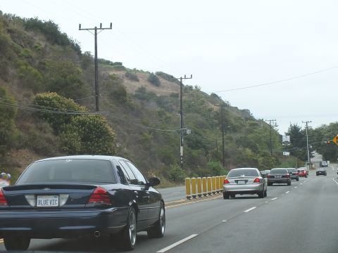 2003 Ford Crown Victoria - Photograph of a blue Crown Victoria and sedans on a coastal road, not a technical document.