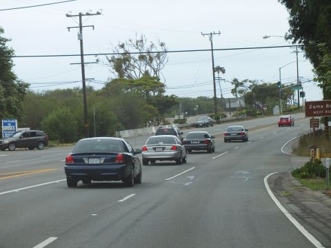 2003 Ford Crown Victoria - Photograph of sedans on a coastal road near a Zuma Beach sign, not a technical document.