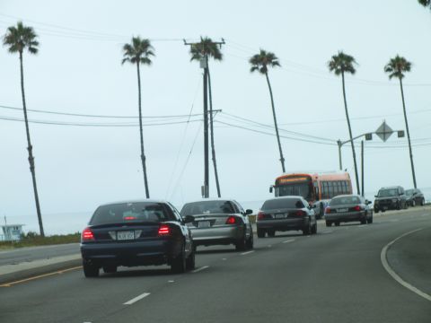 2003 Ford Crown Victoria - Photograph of sedans and a transit bus on a coastal road, not a technical document.