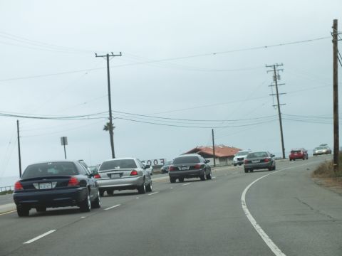 2003 Ford Crown Victoria - Photograph of sedans on a foggy coastal road, not a technical document.