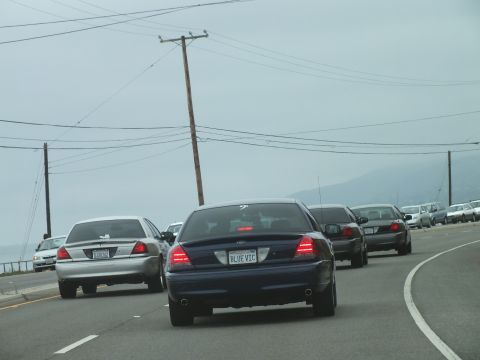2003 Ford Crown Victoria - Photograph of a blue Crown Victoria leading sedans on a foggy coastal highway, not a technical document.