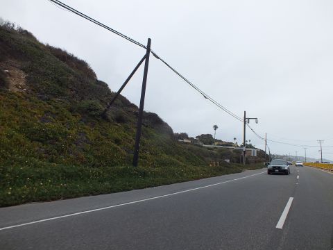 2003 Ford Crown Victoria - Photograph of a coastal highway curve with a leaning utility pole and a distant car, not a technical document.