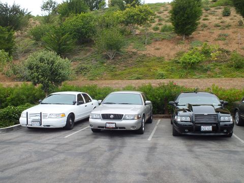 2003 Ford Crown Victoria - Photo of a white, silver, and black sedan parked side by side in a lot at a car meet.