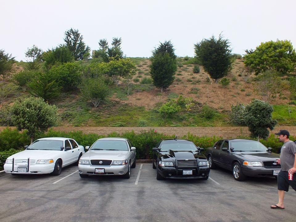 Four sedans parked in a row with a man standing at right