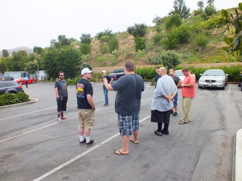 2003 Ford Crown Victoria - Photograph of a group of people standing and talking in a parking lot, not a technical document.