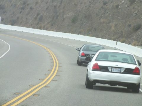 2003 Ford Crown Victoria - Photograph of sedans driving around a curve on a mountain road, not a technical document.
