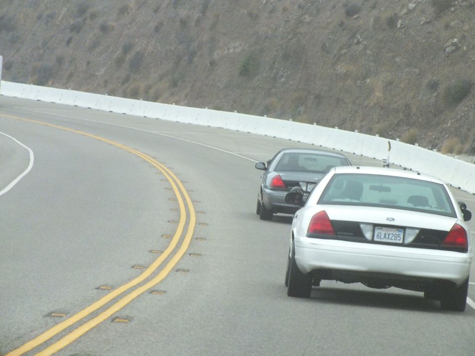 Two sedans rounding a curve on a mountain highway