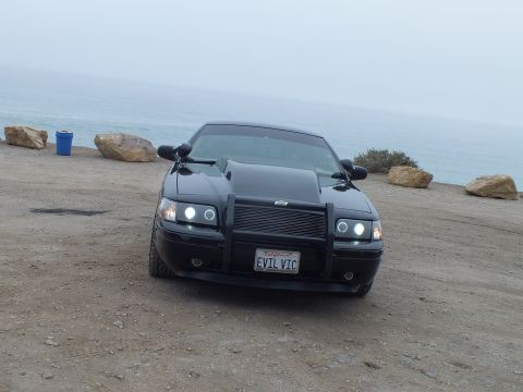 2003 Ford Crown Victoria - Photo of a black customized Crown Victoria front-on at a coastal overlook, not a technical document.