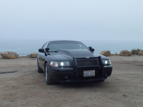 2003 Ford Crown Victoria - Photo of a black customized Crown Victoria parked by the ocean, not a technical document.