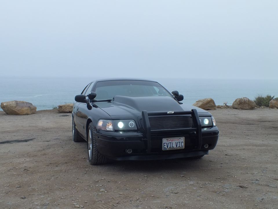 Black 'EVIL VIC' Crown Victoria three-quarter front view by the ocean
