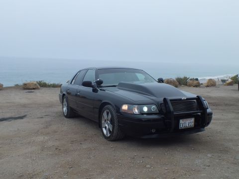 2003 Ford Crown Victoria - Photo of a black customized Crown Victoria parked along the coast, not a technical document.