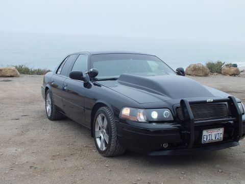 2003 Ford Crown Victoria - Photo of a black customized Crown Victoria at a coastal pullout, not a technical document.