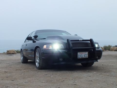 2003 Ford Crown Victoria - Photo of a black customized Crown Victoria with headlights on at a foggy coastal overlook, not a document.