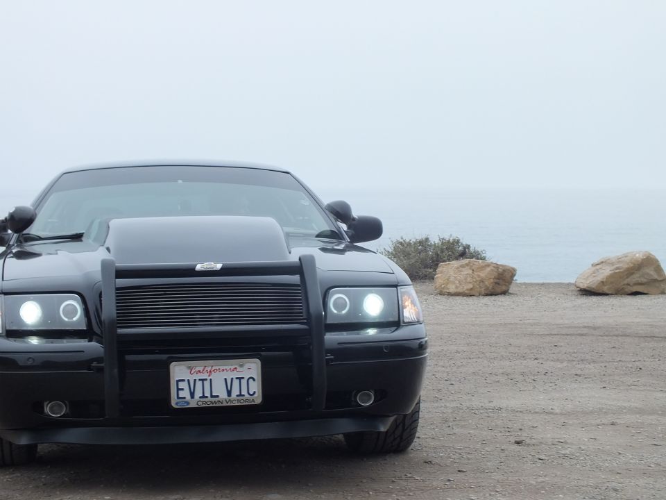 Black 'EVIL VIC' Crown Victoria front three-quarter view near the ocean