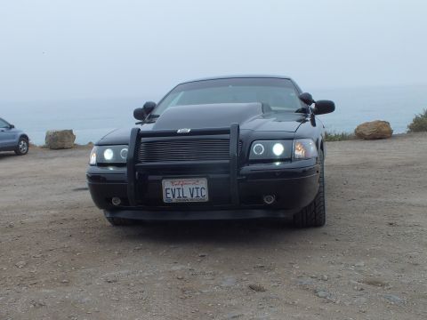 2003 Ford Crown Victoria - Photo of a black customized Crown Victoria front-on at a coastal overlook, not a technical document.