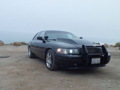 2003 Ford Crown Victoria - Photo of a black customized Crown Victoria parked at a foggy coastal overlook, not a document.