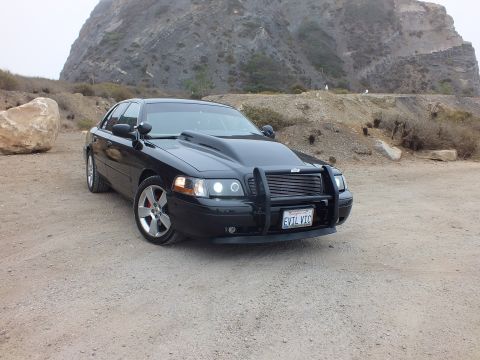 2003 Ford Crown Victoria - Photo of a black customized Crown Victoria parked before a rocky hillside, not a technical document.