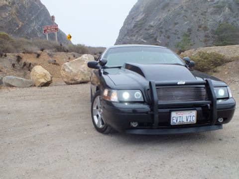 2003 Ford Crown Victoria - Photo of a black customized Crown Victoria at a dirt pullout near road signs, not a technical document.