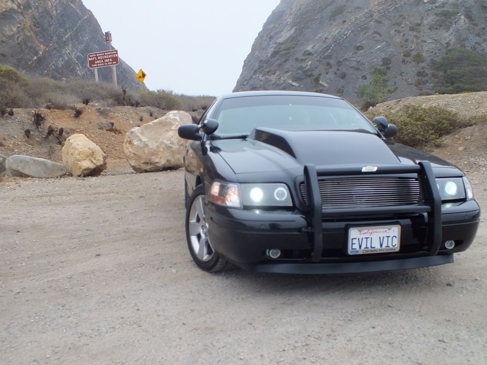 Black 'EVIL VIC' Crown Victoria at dirt pullout with road signs behind