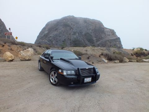 2003 Ford Crown Victoria - Photo of a black customized Crown Victoria parked before a rocky bluff, not a technical document.
