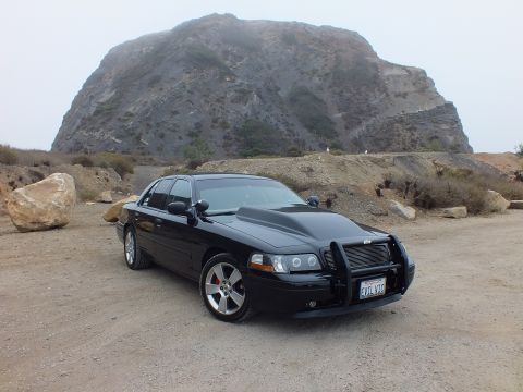 2003 Ford Crown Victoria - Photo of a black customized Crown Victoria at a rocky coastal overlook, not a technical document.