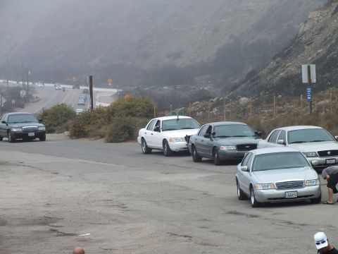 2003 Ford Crown Victoria - Photograph of sedans lined up along a coastal roadway at a car meetup; not a technical document.