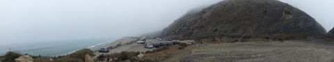 2003 Ford Crown Victoria - Panoramic photograph of a foggy coastal beach with distant parked cars; not a technical document.