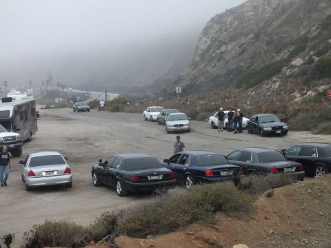 2003 Ford Crown Victoria - Photograph of a car meetup with parked sedans, an RV, and attendees at a foggy coastal lot; not a technical document.
