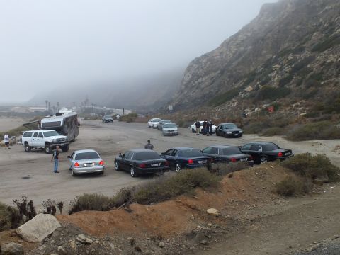 2003 Ford Crown Victoria - Photograph of sedans and pickups parked at a foggy coastal lot car meetup; not a technical document.