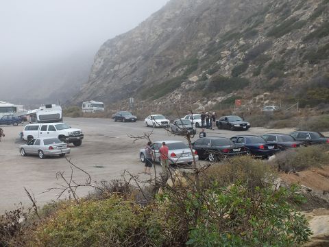 2003 Ford Crown Victoria - Photograph of a car meetup with sedans, pickups, an RV, and attendees at a foggy coastal lot; not a technical document.